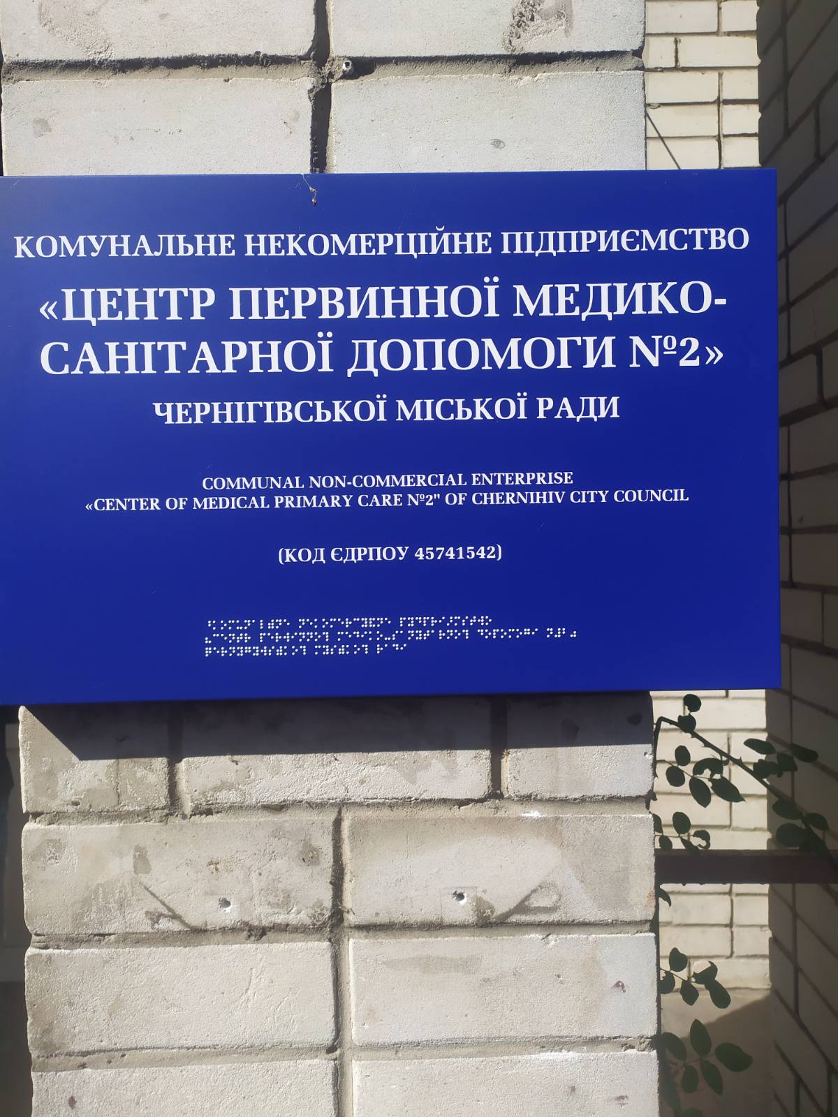 Інформаційна вивіска закладу зі шрифтом Брайля на вході